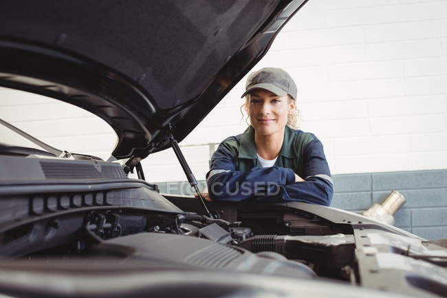 Портрет женщины-механика, стоящей со скрещенными руками в ремонтном гараже — стоковое фото