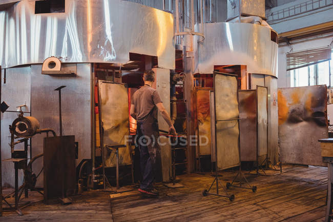 Glassblower heating glass in glassblowers oven at glassblowing factory — Stock Photo