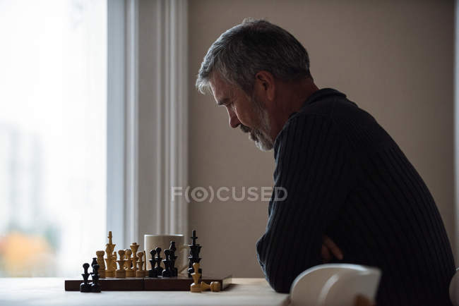 Homem atencioso jogando xadrez em casa — Fotografia de Stock