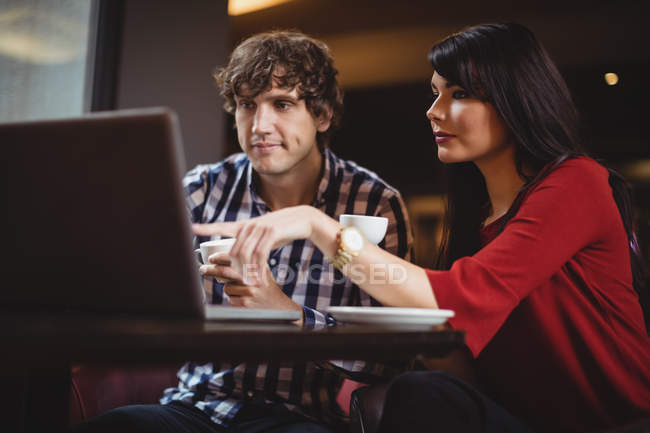 Couple using laptop while having coffee in restaurant — Stock Photo