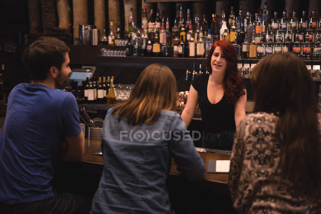 Barman interagissant avec les clients au comptoir du bar — Photo de stock
