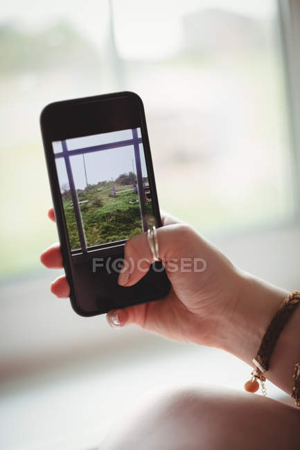 Hand of woman taking photo on mobile phone from window — Stock Photo
