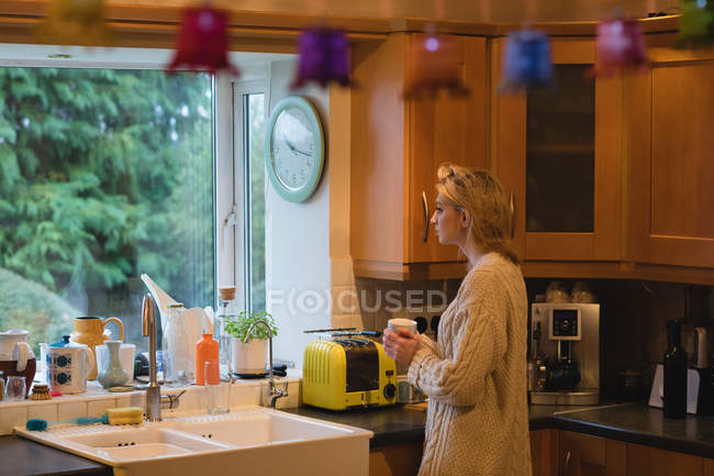 Жінка тримає чашку кави в кухні в домашніх умовах — стокове фото