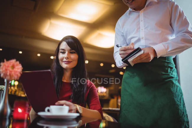 Camarero tomando orden de una mujer en un restaurante - foto de stock