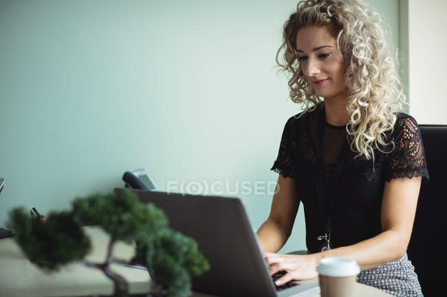 Бізнес-леді, що працює на ноутбуці в інтер'єрі офісу — стокове фото
