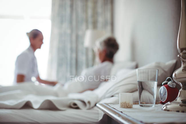 Medicine and glass of water on table in bed room — Stock Photo