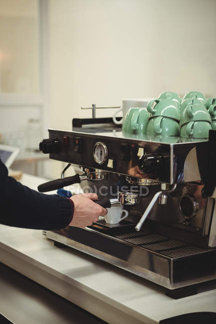 Рука человека держит портативный фильтр под кофеваркой в кофейне — стоковое фото