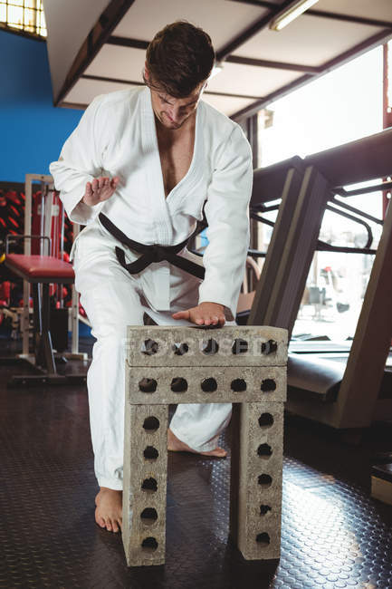Karate player breaking concrete block in fitness studio — Stock Photo