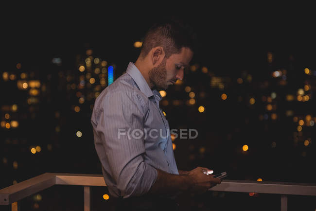 Людина, використовуючи свій мобільний телефон на балконі вночі — Stock Photo