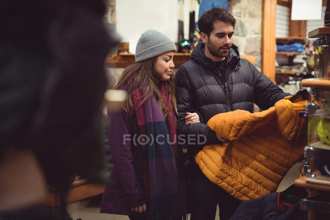 Coppia selezionando abbigliamento insieme in un negozio di abbigliamento — Foto stock
