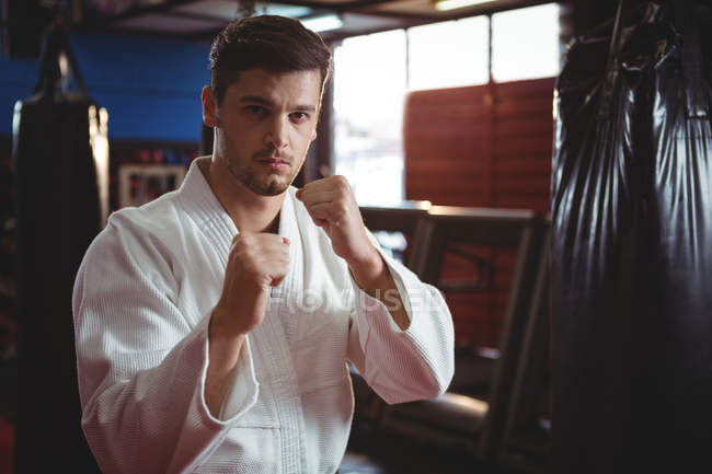 Reproductor de karate realizando postura de karate en gimnasio - foto de stock