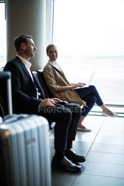 Pendolari che interagiscono tra loro nella sala d'attesa del terminal aeroportuale — Foto stock
