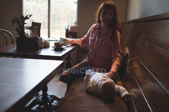 Мати дивиться на дитину і тримає цифровий планшет у кафе — стокове фото
