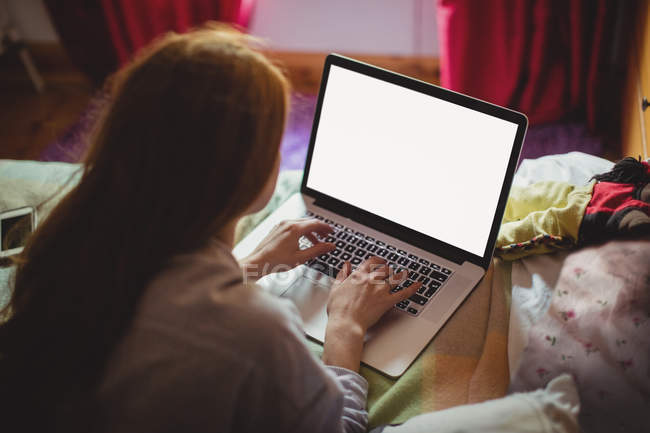 Женщина использует ноутбук в спальне дома — стоковое фото