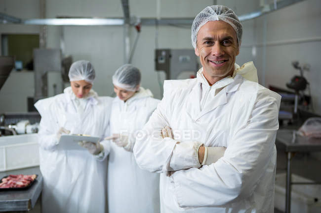 Portrait of smiling butcher standing with arms folded — Stock Photo