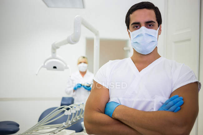 Ritratto di dentista maschio in piedi con le braccia incrociate in clinica dentale — Foto stock