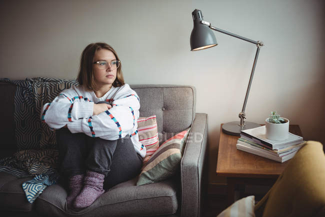 Ragionevole donna seduta e abbracciare le ginocchia in soggiorno a casa — Foto stock