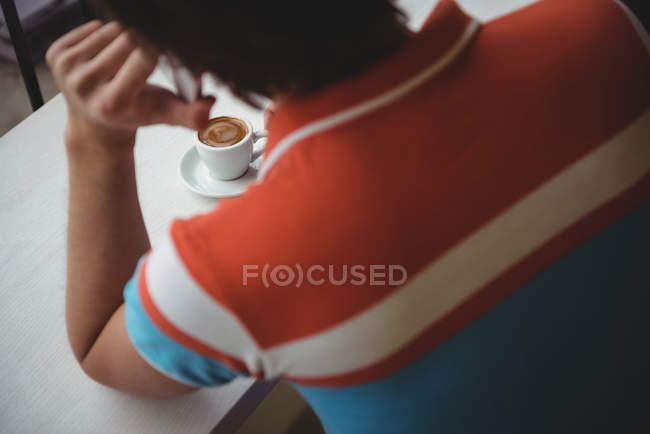 Uomo che parla al telefono cellulare con tazza di caffè sul tavolo in caffetteria — Foto stock