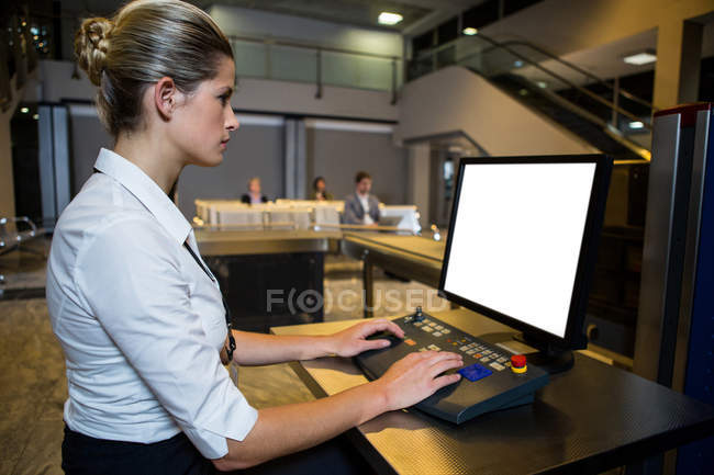 Personal femenino trabajando en el mostrador de seguridad en la terminal del aeropuerto - foto de stock