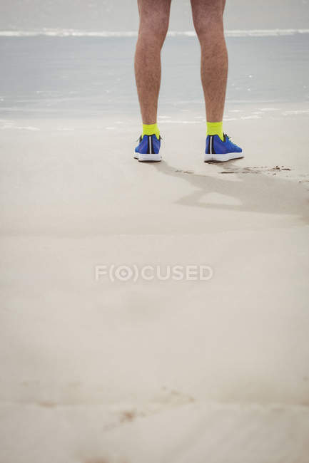 Low section of athlete standing on sandy beach — Stock Photo