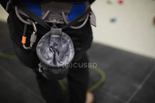 Seção média do homem de pé contra a parede de escalada artificial no ginásio — Fotografia de Stock