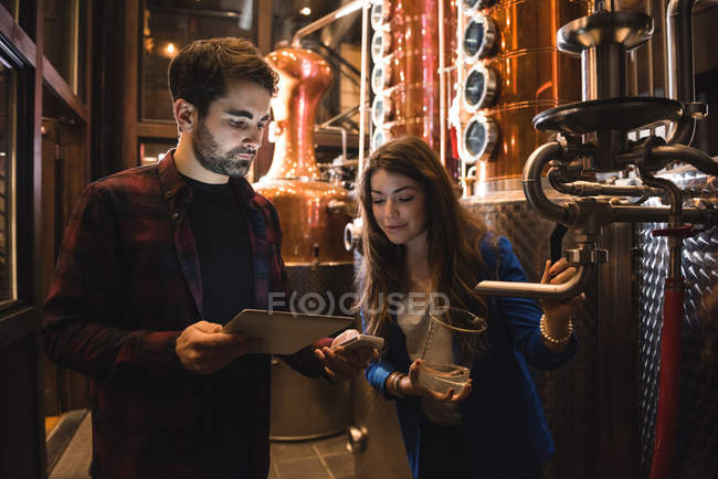 Uomo e donna discutono su tablet digitale nella fabbrica di birra — Foto stock