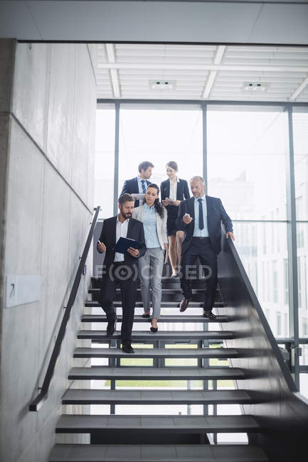 Selbstbewusste Geschäftsleute stehen im Büro auf der Treppe — Stockfoto