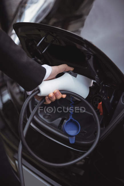 Main de femme recharge voiture électrique à la station de recharge de véhicule électrique — Photo de stock