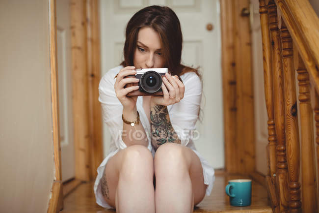 Femme prenant des photos sur appareil photo numérique à la maison — Photo de stock
