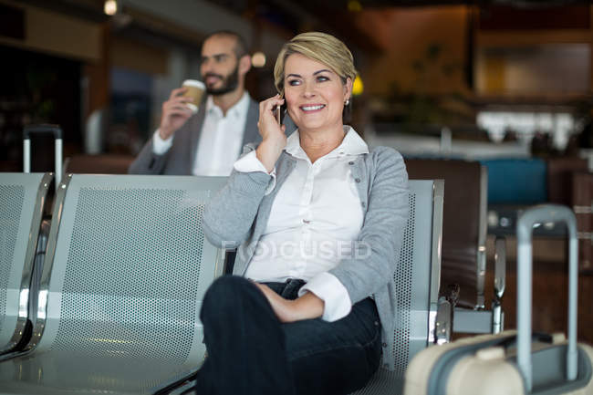 Lächelnde Geschäftsfrau telefoniert im Wartebereich am Flughafen-Terminal — Stockfoto