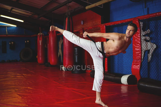 Joueur de karaté pratiquant le kickboxing dans un studio de fitness — Photo de stock