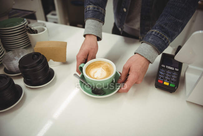 Mains servant du café avec un magnifique latte art au café — Photo de stock