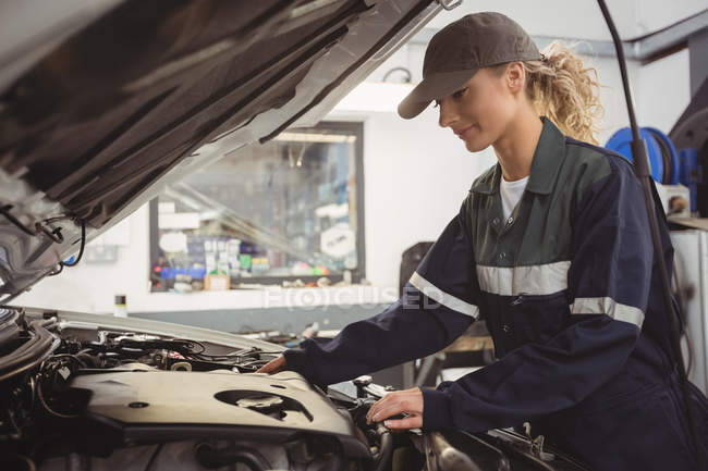 Belo carro mecânico feminino de manutenção na garagem de reparação — Fotografia de Stock