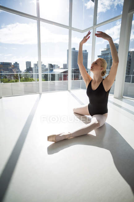 Ballerina stretching on the floor while practicing ballet dance at studio — Stock Photo