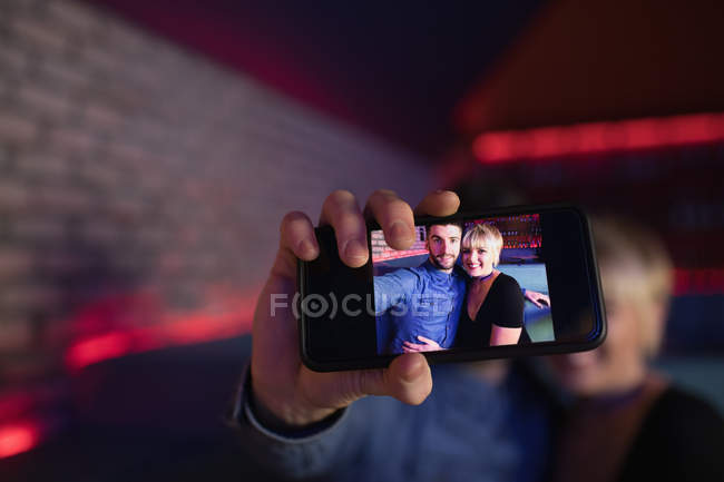 Lächelndes Paar macht Selfie mit Handy in Bar — Stockfoto