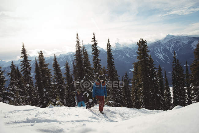 Couple running on snow covered mountain against trees — Stock Photo