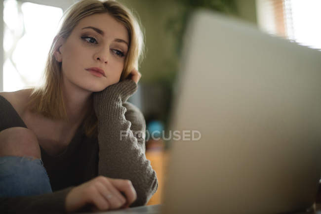 Mujer mirando el ordenador portátil en la mesa en casa - foto de stock