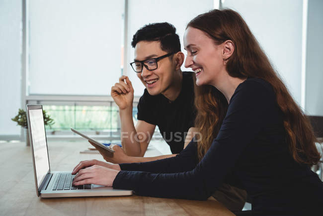 Счастливые руководители бизнеса обсуждают за ноутбуком в офисе — стоковое фото