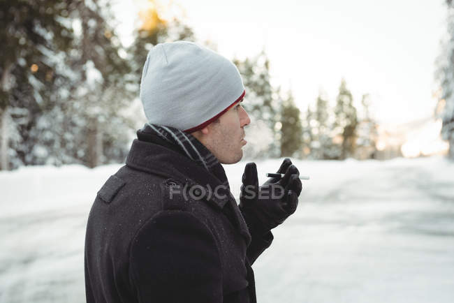 Thoughtful man smoking a cigarette in forest during winter — Stock Photo