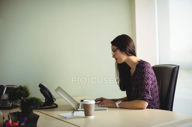 Бізнес-леді, що працює на ноутбуці в офісі — стокове фото