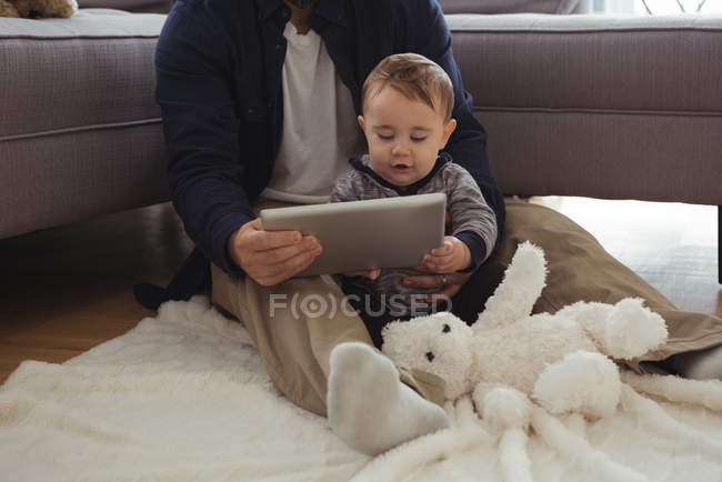 Pai e bebê usando tablet digital na sala de estar em casa — Fotografia de Stock