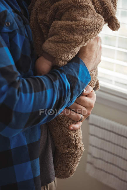 Seção média do pai segurando bebê enquanto estava na cozinha em casa — Fotografia de Stock