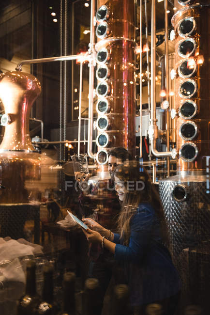 Homem e mulher examinando amostra de álcool na fábrica de cerveja — Fotografia de Stock