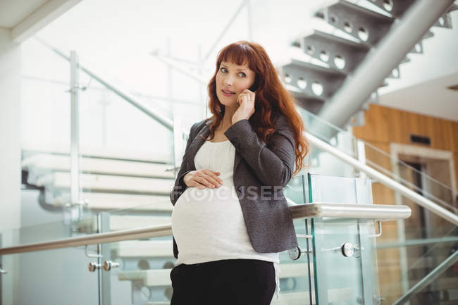 Schwangere Geschäftsfrau telefoniert in der Nähe von Treppen im Büro — Stockfoto