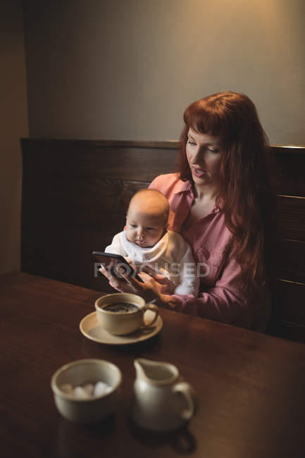 Madre con bambina utilizzando il telefono cellulare nel caffè — Foto stock