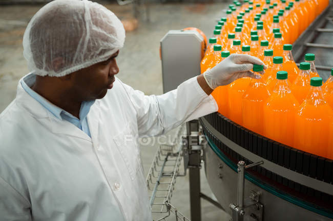 Vista de ángulo alto del trabajador masculino serio examinando botellas en la fábrica de jugo - foto de stock