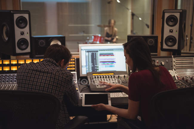 Аудіоінженери, що використовують цифровий планшет, сидять у студії звукозапису — стокове фото