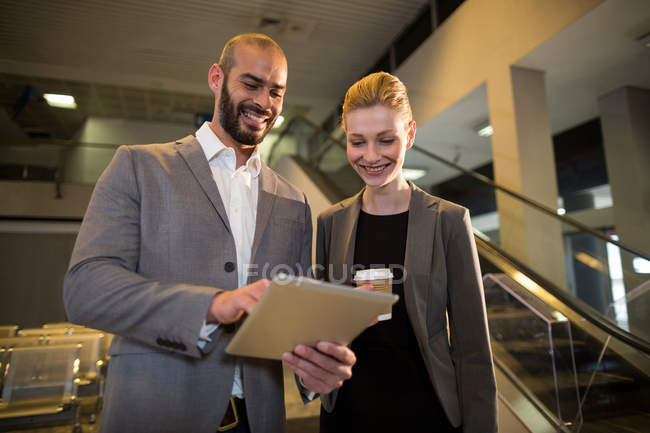 Ділові люди обговорюють цифровий планшет в аеропорту — стокове фото