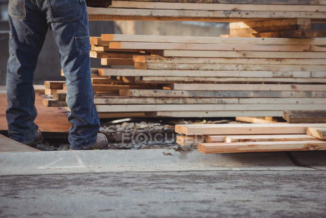 Section basse du travailleur de la construction organisant le bois sur le chantier — Photo de stock