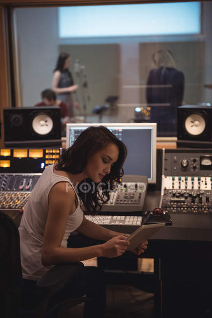 Ingeniero de audio usando tableta digital cerca del mezclador de sonido en el estudio de grabación - foto de stock
